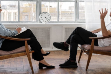 Terapeuta utilizando laptop para marketing digital, com ícones de redes sociais e SEO ao redor.