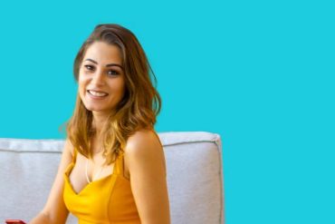 Imagem profissional de um corretor de imóveis sorrindo, com um tablet mostrando gráficos de mercado e um fundo de imóveis modernos