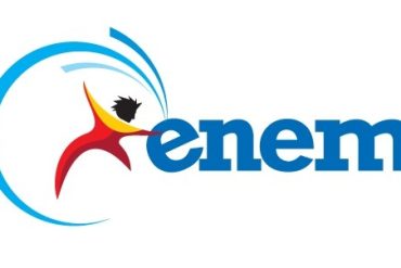 Estudante sorrindo, com livros do ENEM e um laptop aberto mostrando o curso ENEM Interpretativo.