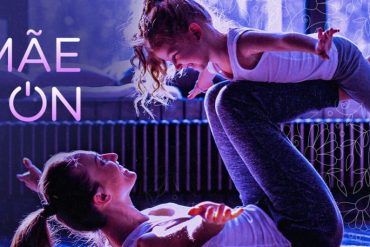 Mulher sorrindo realizando exercício de agachamento com elástico, vestindo roupas esportivas em um ambiente claro e moderno.