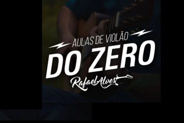 Homem sorrindo tocando violão em um ambiente de estudo com o curso Violão do Zero ao lado