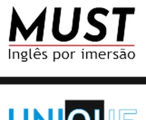 Estudante sorridente praticando inglês com livro e notebook, com bandeira do Reino Unido ao fundo.