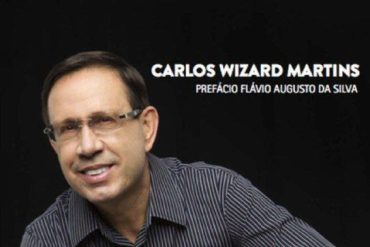 Carlos Wizard em frente à logo da Wizard Escola de Idiomas, símbolo de empreendedorismo e sucesso financeiro.